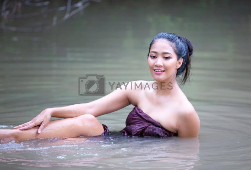 Asian sits by the water