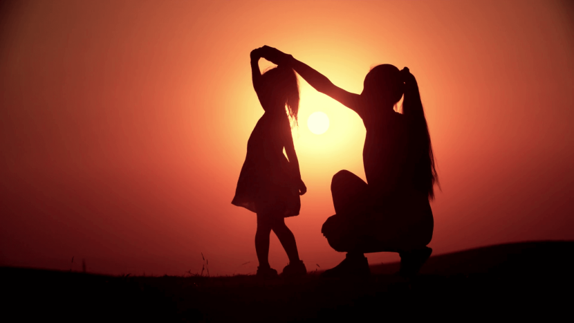 Daughter and mother silhouette at sunset