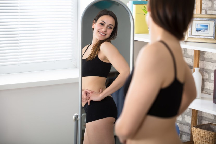 A woman examines herself in a mirror