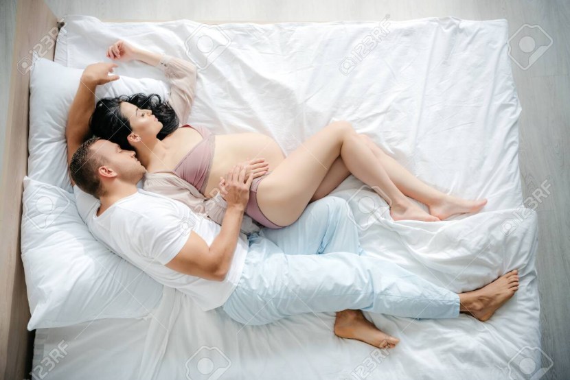 Photo shoot of pregnant women with her husband on the bed