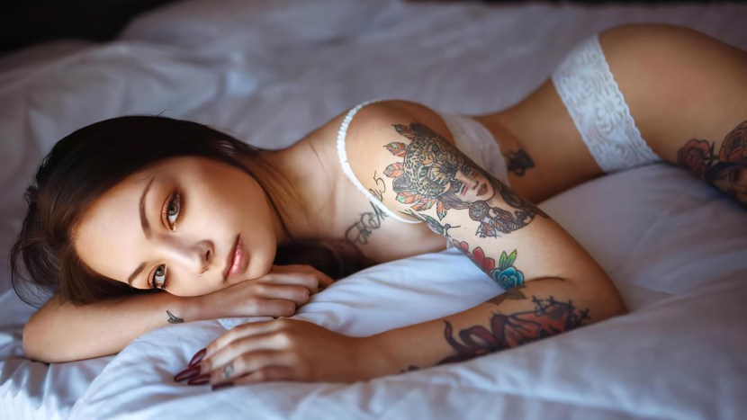 The girl lies in white underwear and in tattoos