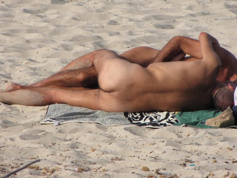 A naked guy lies on the beach