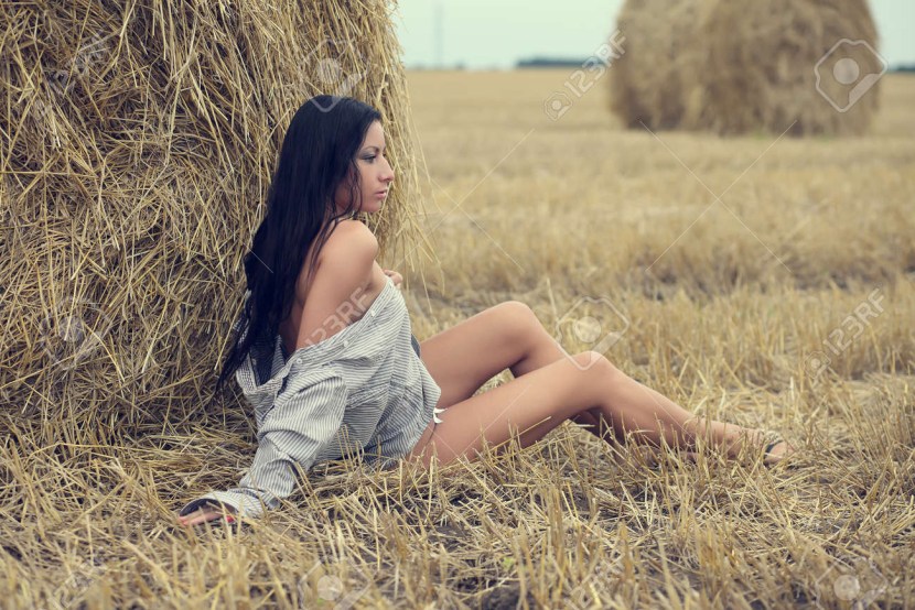 Naked woman sits in the field