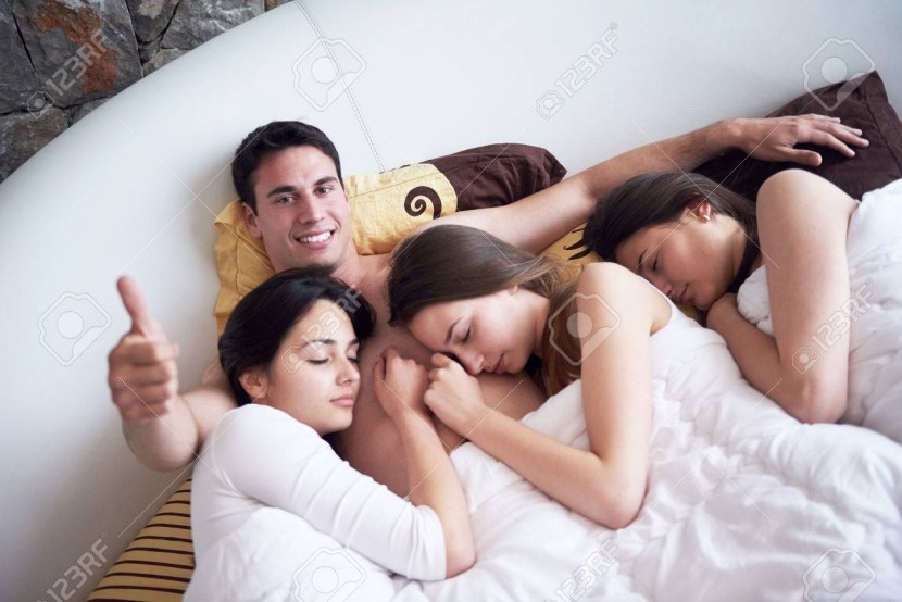 Two girls and guy in bed
